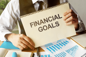 Person holding up notebook with bold text saying financial goals