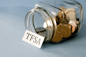 a glass jar of coins laying on its side with a label leaning against the opening with TFSA written on it
